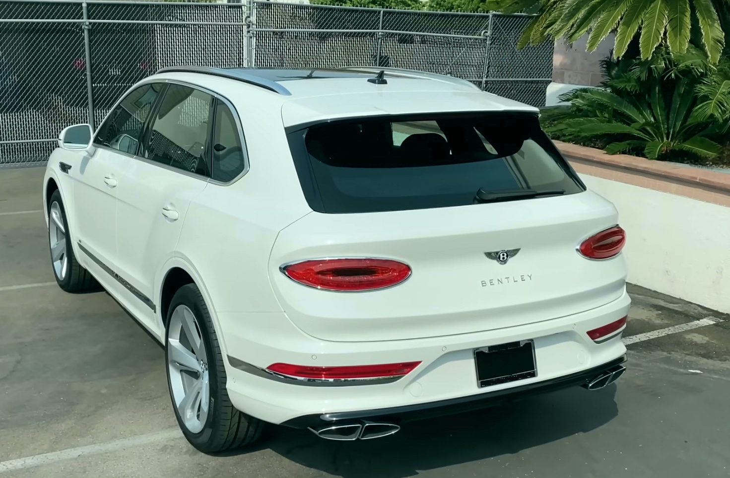 Bentley Bentayga | Temecula Auto Repair & Transmission A white Bentley Bentayga parked in front of the fence entrance.
