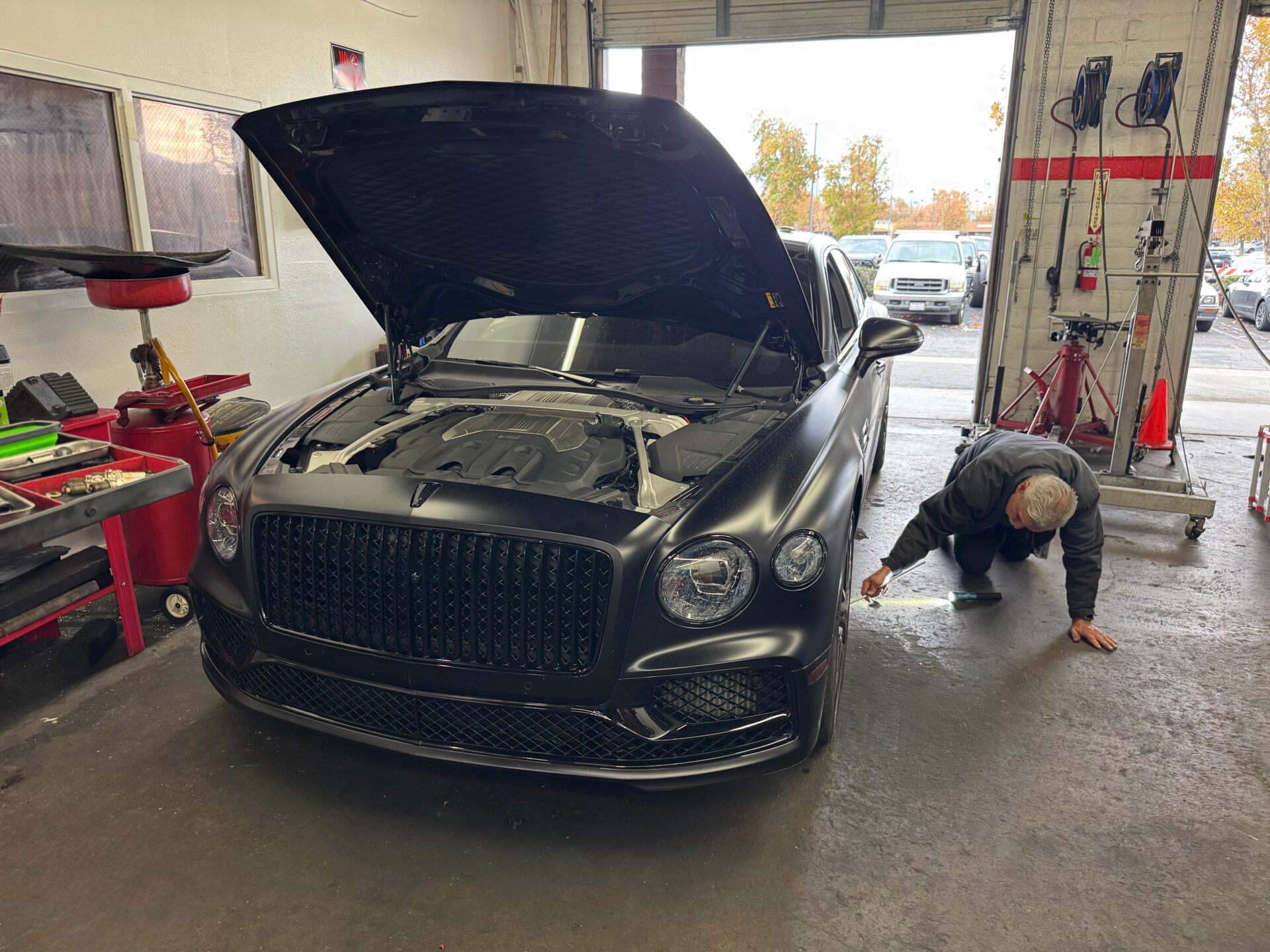 A technician working on a modern Bentley Flying Spur.