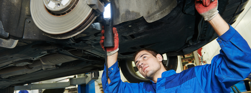 An Automotive Technician inspecting brakes on a car.