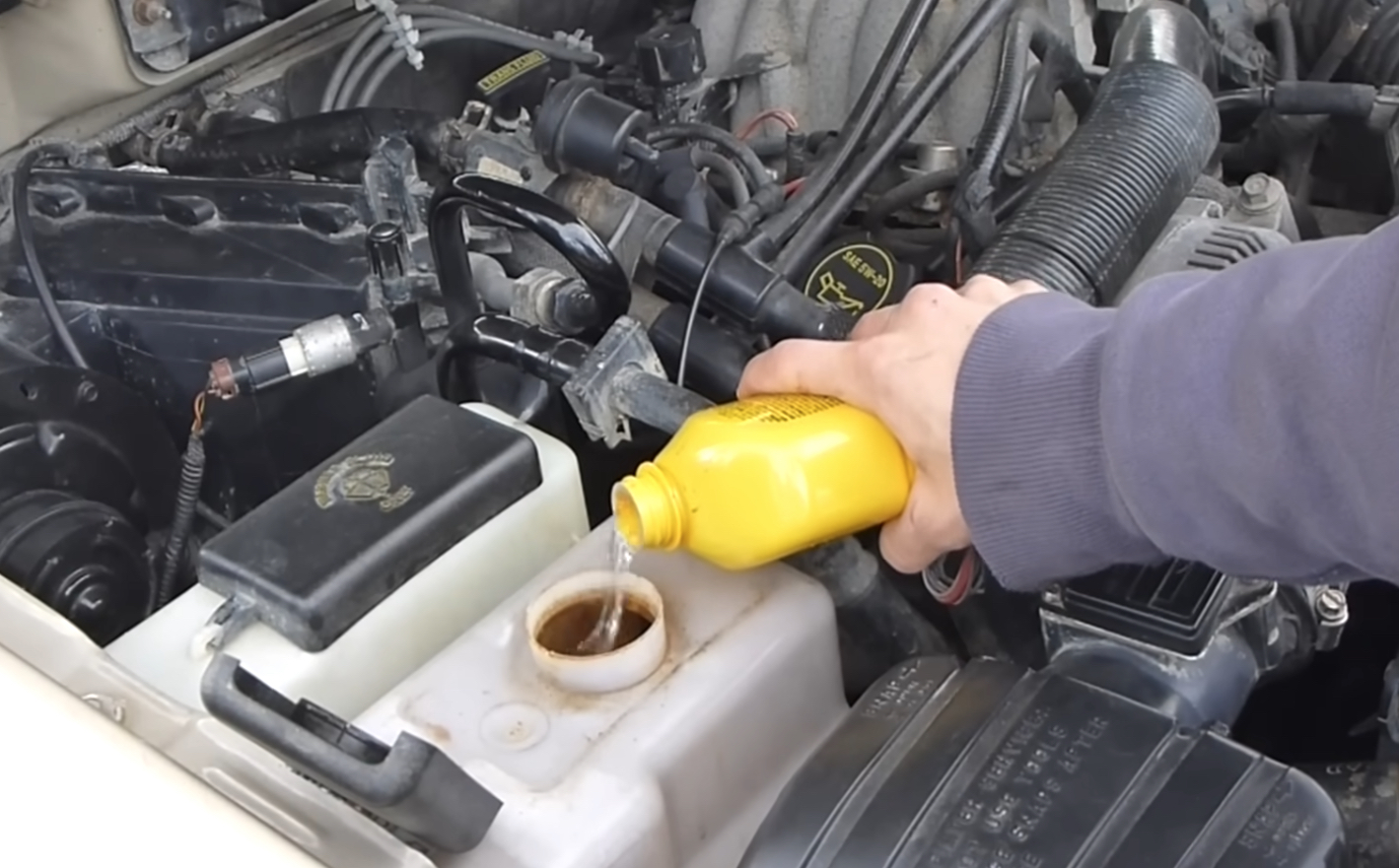 A technician adds Coolant into the Cooling System Recovery Tank