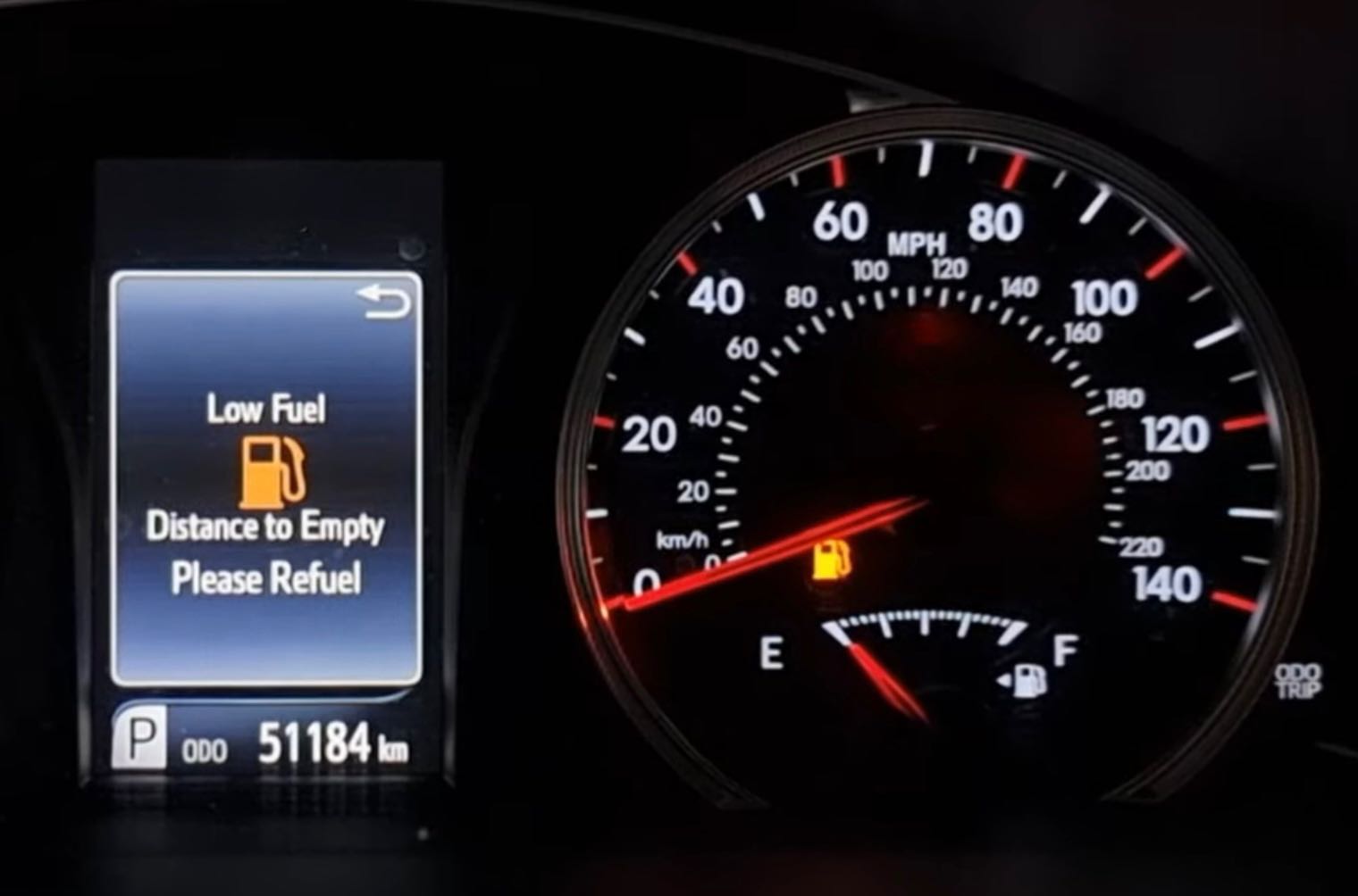 A fuel gauge on empty with the low-fuel warning light on.
