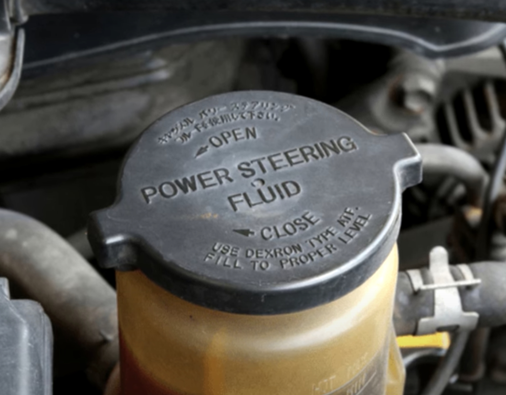 Power Steering Fluid - Temecula Auto Repair | Temecula Auto Repair & Transmission Image if a car's Power Steering Fluid Reservoir with dark fluid.