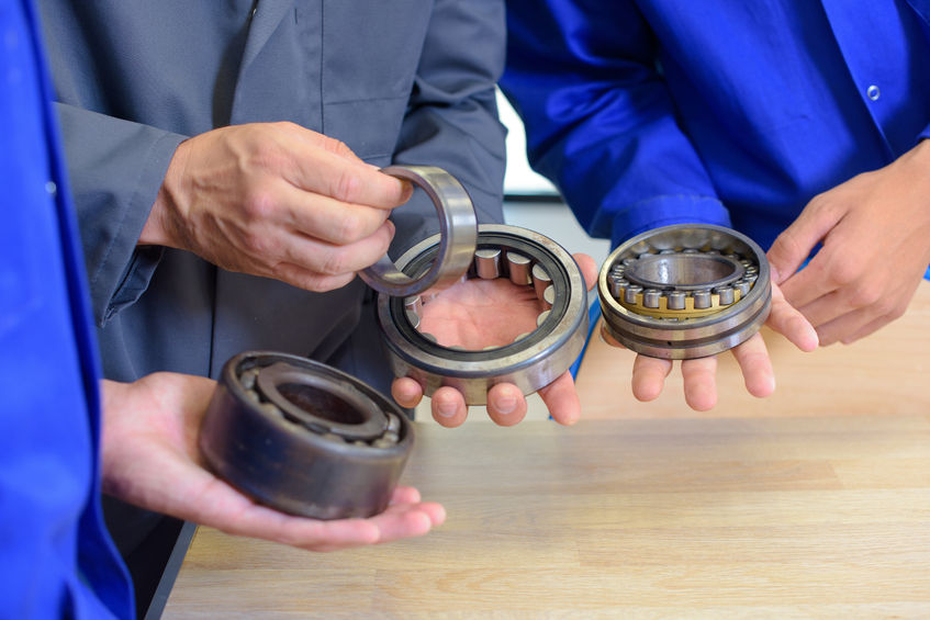 Technicians holding an array of wheel bearings for illustration.
